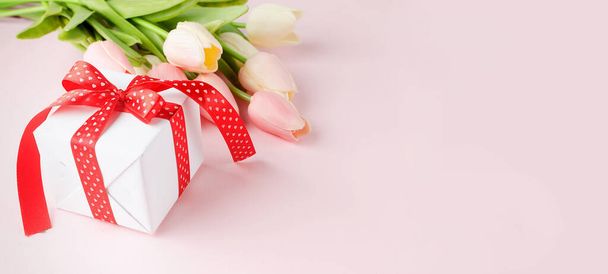 Confezione regalo con bouquet di tulipani rosa e bianchi su sfondo rosa pastello. Concetto di primavera o di vacanza, 8 marzo, Giornata internazionale della donna, compleanno. Copia spazio, lastra piatta, Mockup modello biglietto di auguri con posto per il testo
,  - Foto, immagini