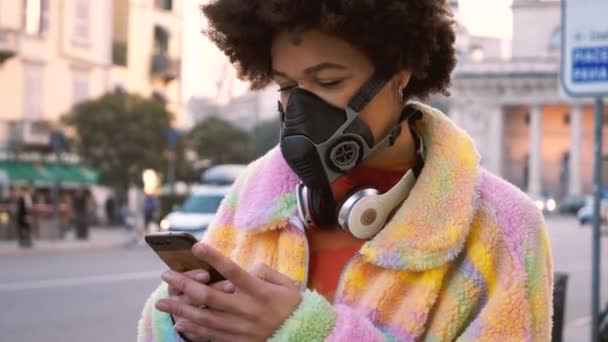 Zpomalený pohyb mladé ženy pózující venku v Miláně s lékařskou maskou chránící před znečištěním a virem pomocí smartphonu - anti-smog, infekce, koncepce ochrany - Záběry, video