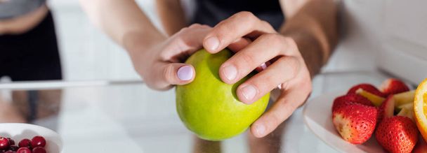 panoramiczne ujęcie mężczyzny i kobiety dotykających jabłka w lodówce  - Zdjęcie, obraz