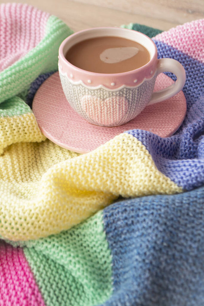 Knitted effect cup with latte, colorful pastel giant plaid, morning concept, vertical image - Foto, afbeelding