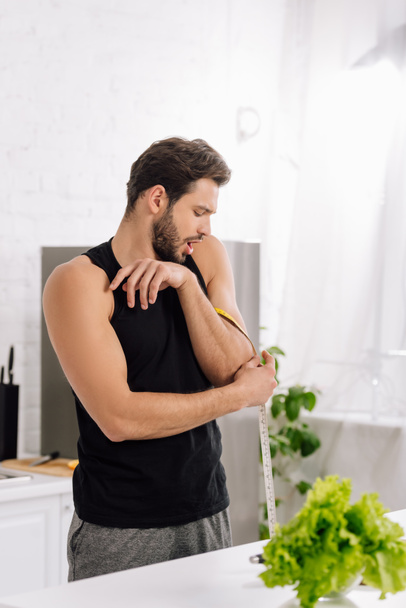 foyer sélectif de l'homme surpris mesurant le muscle à portée de main dans la cuisine
  - Photo, image