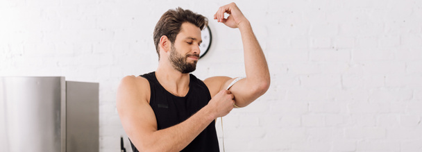 plan panoramique de bel homme sportif mesurant le muscle à portée de main
  - Photo, image
