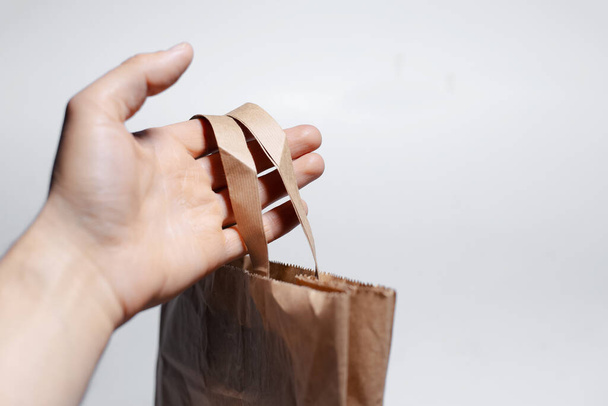 Close-up of male hand holding eco paper bag on white background. - Photo, Image