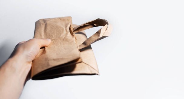 Close-up of male hand holding eco paper bag on white background. - Photo, Image