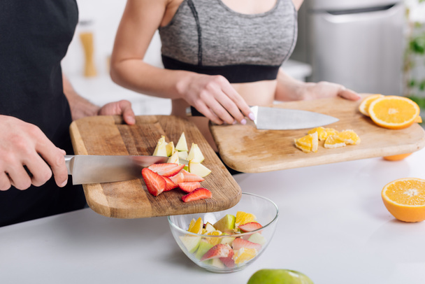 rajattu näkymä miehen ja naisen ruoanlaitto hedelmäsalaattia
  - Valokuva, kuva