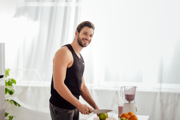 happy bearded man holding knife near fresh apple  - Zdjęcie, obraz