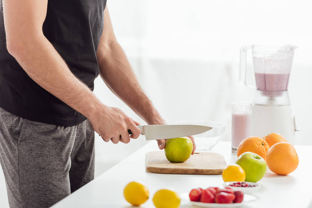cropped view of man cutting apple near fresh fruits and smoothie  - Photo, image