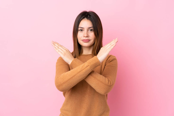 Jonge vrouw over geïsoleerde roze achtergrond maken GEEN gebaar - Foto, afbeelding