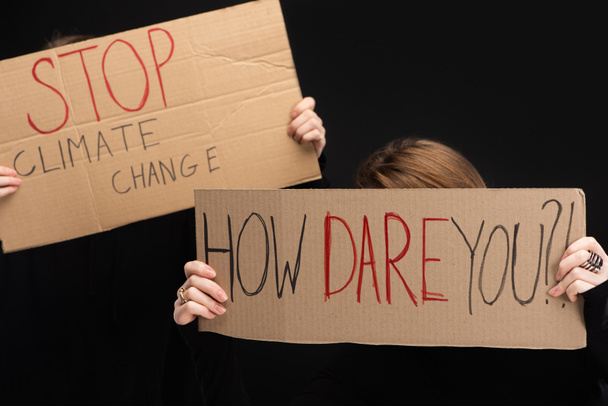 Частичный взгляд на женщин с плакатами с остановкой изменения климата и как вы смеете писать изолированные на черном, концепции глобального потепления
 - Фото, изображение