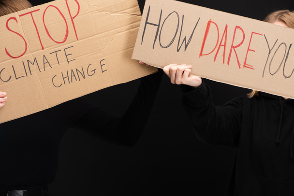Cropped view of women with placards with stop climate change and how dare you lettering isolated on black, global warming concept - Photo, Image