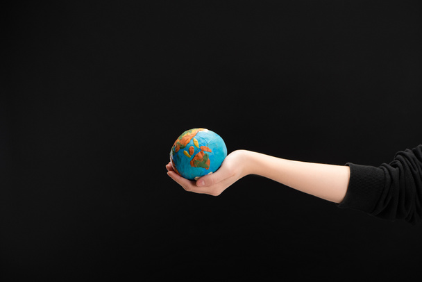 Partial view of woman with outstretched hand holding plasticine globe isolated on black, global warming concept - Fotografie, Obrázek