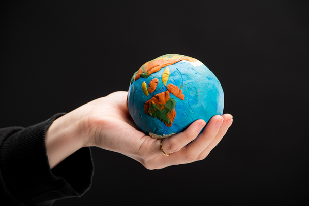 Partial view of plasticine globe in female hand isolated on black, global warming concept - Foto, immagini