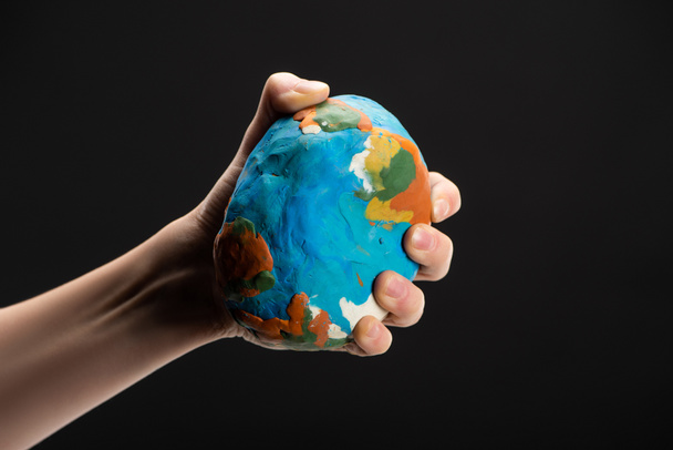 Vista cortada da mulher comprimindo globo de plasticina na mão isolado em preto, conceito de aquecimento global
 - Foto, Imagem