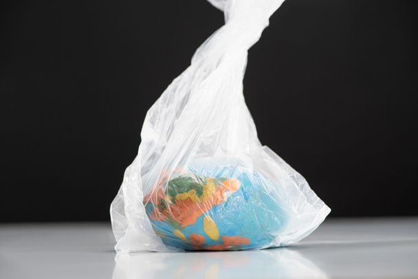 Globo de plasticina em saco plástico isolado em preto, conceito de aquecimento global
 - Foto, Imagem
