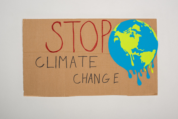 Bovenaanzicht van plakkaat met geschilderde wereldbol en stop klimaatverandering belettering op grijze achtergrond, global warming concept - Foto, afbeelding