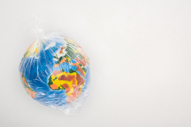 Vista superior del globo en bolsa de plástico sobre fondo blanco, concepto de calentamiento global
 - Foto, Imagen