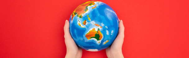 Vista panorámica de la mujer sosteniendo globo aislado en rojo, concepto de calentamiento global
 - Foto, Imagen