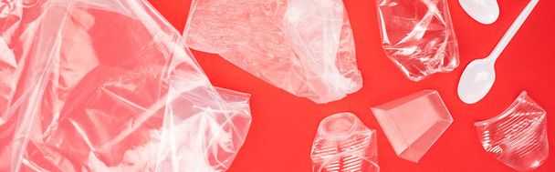 Panoramisch uitzicht op plastic afval geïsoleerd op rood, global warming concept - Foto, afbeelding