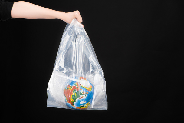 Siyah, küresel ısınma kavramına izole edilmiş plastik çöp ve küre içeren plastik poşet taşıyan kadın görüntüsü - Fotoğraf, Görsel