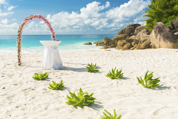 Guirlande florale et une table blanche comme décoration de mariage sur une plage tropicale Anse Georgette sur l'île de Praslin aux Seychelles - Photo, image