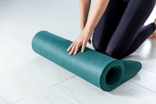 Closeup picture of yoga green mat. Woman is getting ready for exercises indoor. - Photo, Image