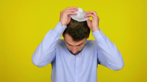 Mann zieht Schutzmaske ab und atmet auf gelbem Hintergrund tief durch - Filmmaterial, Video