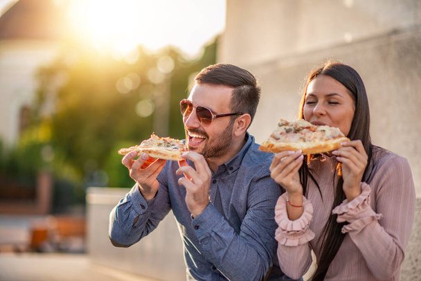 Feliz por estar no amor.Retrato de casal amoroso sorriso.Casal feliz comendo pizza ao ar livre.Férias, diversão, viagens e conceito de pessoas
. - Foto, Imagem