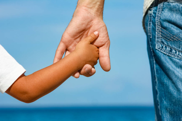 happy dad holds the hand of a child by the greek sea in nature - Fotoğraf, Görsel
