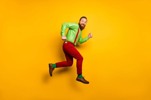 Full size photo of cheerful irish man jump run after discount wear good look clothing suspendsers trousers shoes isolated over bright color background - Foto, Imagem