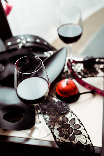 επιλεκτική εστίαση της μάσκας κουνελιού κοντά στην καμπάνα φιλί και κόκκινο κρασί σε ποτήρια - Φωτογραφία, εικόνα