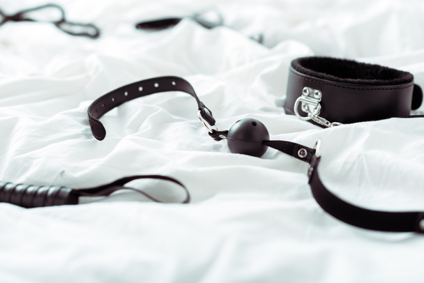 selective focus of bdsm leash and gag on white bedding  - Photo, Image