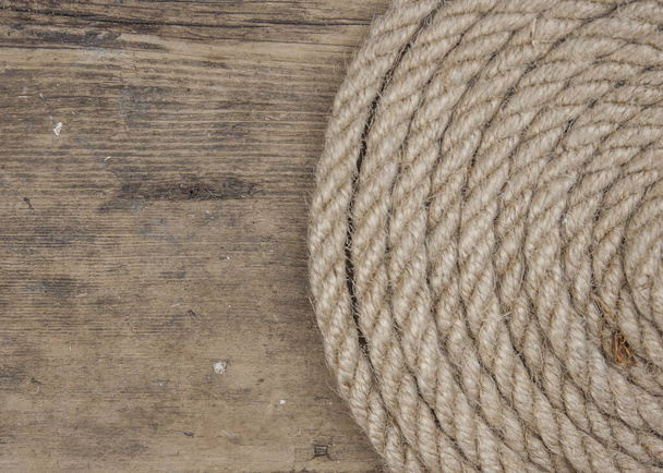 Close-up of a thick hemp rope. Natural rope on an old wooden table. Side view. Soft focus.  - Valokuva, kuva