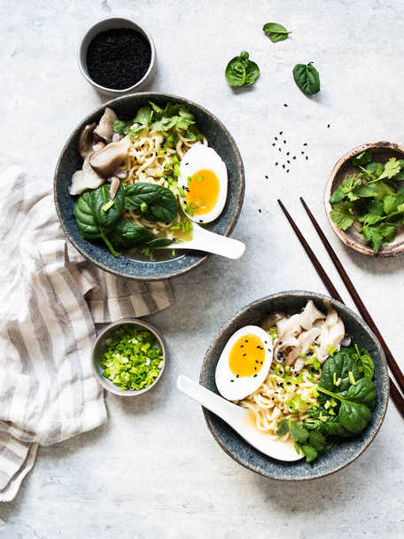 Vegetarische Miso Ramen met champignons, rauwe spinazie en gekookt ei in blauwe kom op grijze tafel. Bovenaanzicht - Foto, afbeelding