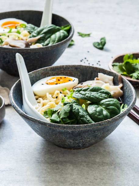 Vegetarian Miso Ramen with Mushrooms, raw Spinach and boiled Egg in blue bowl on grey table - Zdjęcie, obraz