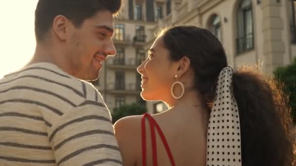 Yazlık giysiler içinde mutlu genç bir çift sokakta yürürken gülüyor ve birbirlerine bakıyorlardı. - Video, Çekim