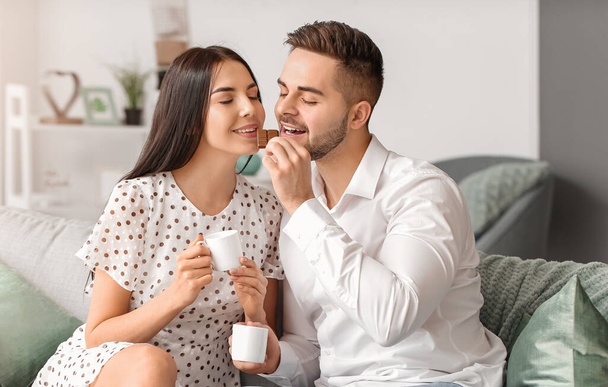 Beautiful young couple eating chocolate at home - Photo, Image