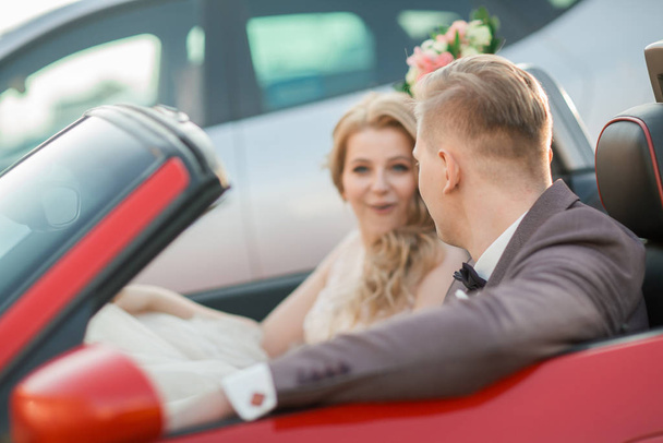 happy bride and groom sitting in a luxury car. - Фото, изображение