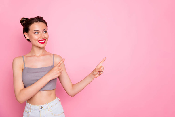 Photo of attractive lady cute buns red lips amazing shapes indicating fingers empty space show low prices wear casual grey short top naked belly isolated pink color background - Fotografie, Obrázek