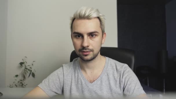 A guy with white hair works at a laptop in a home office - Footage, Video