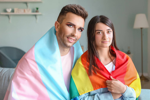 Portrait de jeune couple transgenre avec drapeaux à la maison
 - Photo, image