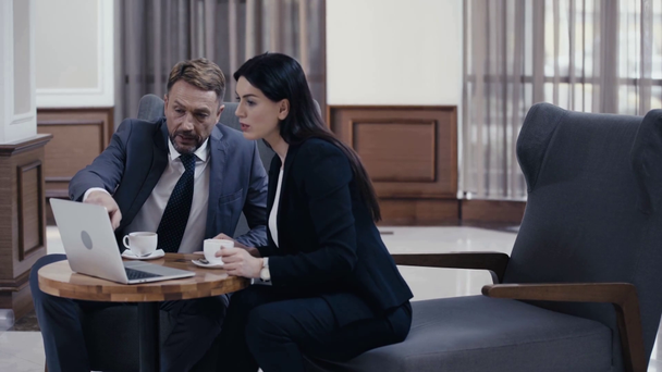 Podnikatelé pomocí notebooku a pití kávy během setkání v lobby - Záběry, video
