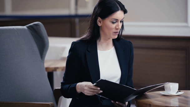 Podnikatelka drží dokumenty a mluví s někým v lobby restaurace - Záběry, video