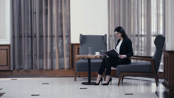 Zakenvrouw werkt met documenten en drinkt koffie in restaurant lobby - Video