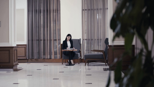 Geschäftsfrau mit Dokumenten in Lobby eines Restaurants  - Filmmaterial, Video
