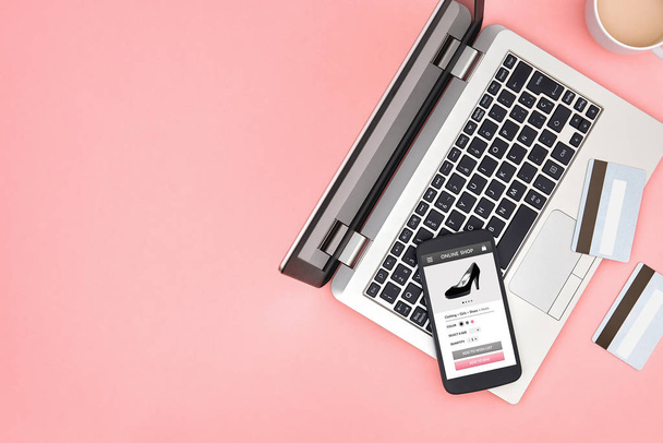 Tienda en línea para las mujeres en la pantalla del teléfono inteligente sobre fondo rosa con ordenador portátil, tarjetas de crédito y espacio de copia. Vista superior
. - Foto, Imagen