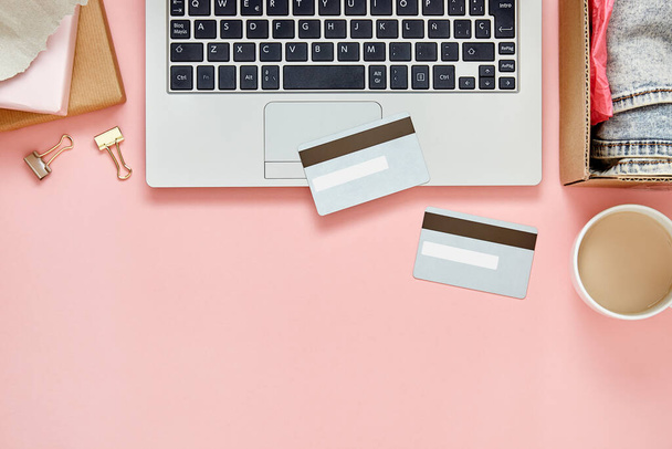 Концепция покупок онлайн на розовом столе с ноутбуком, кредитными картами, посылками и копировальным пространством. Вид сверху
. - Фото, изображение