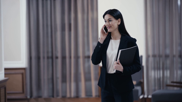 Bizneswoman z papierami rozmawia na smartfonie w lobby restauracji - Materiał filmowy, wideo
