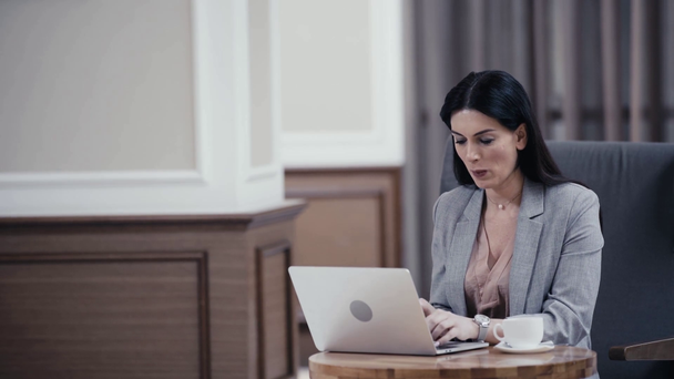 Businesswoman using laptop in restaurant lobby - Кадры, видео