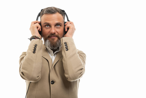 Ritratto di uomo che indossa abiti casual intelligenti ascoltando cuffie isolate su sfondo bianco con spazio di copia area pubblicitaria
 - Foto, immagini