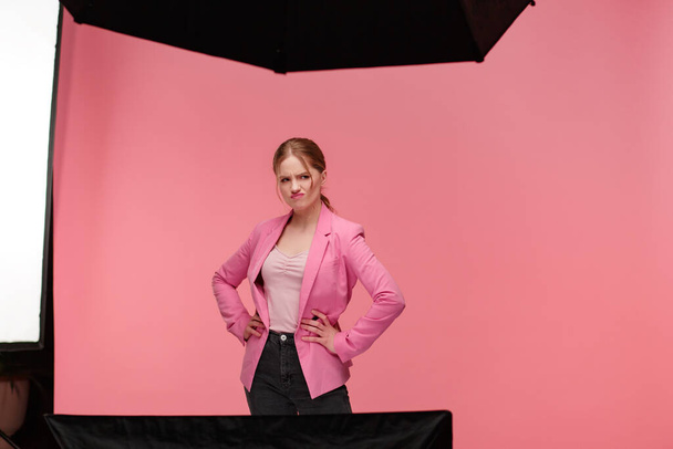 Young beautiful redhead smiling women posing at studio. Funny female blogger with wavy hairstyle and gentle make up filming isolated over pink background. Pink lifestyle - Foto, afbeelding